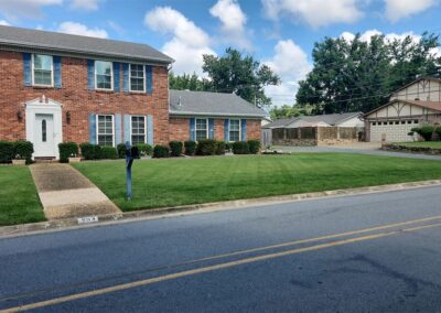 Lawn care service by APEX Lawn Care showcasing a well-maintained green lawn in front of a brick house in Little Rock, Arkansas.