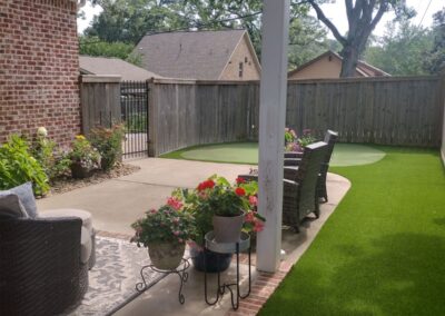 Lush green artificial turf and landscaped patio area with potted flowers, showcasing APEX Lawn Care's professional lawn care services in Little Rock, Arkansas.