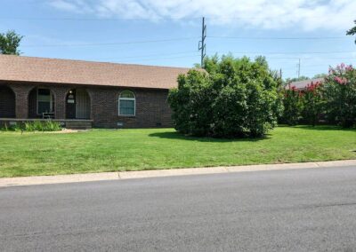 Lawn care service showcasing a well-maintained green lawn and shrubbery in front of a brick home in Little Rock, Arkansas.
