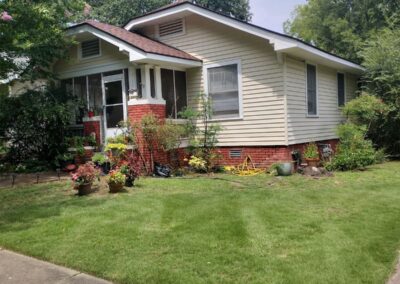 Lawn care service showcase featuring a well-maintained residential yard with landscaped flower beds and a tidy lawn, highlighting APEX Lawn Care's expertise in Central Arkansas.