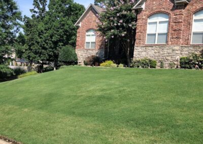 Lush green lawn and well-maintained landscaping in front of a brick home, showcasing APEX Lawn Care services in Little Rock, Arkansas.