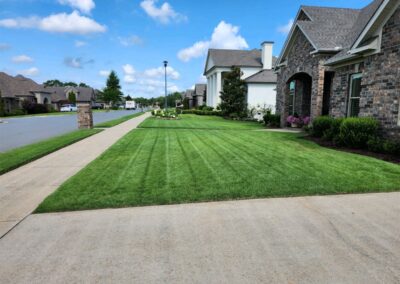 Lush green lawn with neatly striped grass, showcasing professional lawn care services in a residential area of Little Rock, Arkansas.