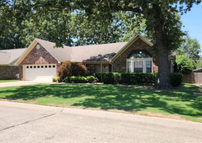 Suburban single-story office with a brown roof, beige sidings, and an attached double garage on a sunny day. - Little Rock Lawn Care and Mowing Services by Apex Lawn Care