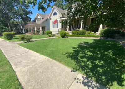 Suburban house with a well-kept lawn and a stone pathway on a sunny day is often inhabited by an employee. - Little Rock Lawn Care and Mowing Services by Apex Lawn Care