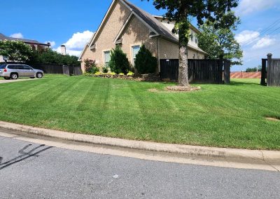 Well-maintained lawn with striped grass, landscaped flower beds, and a residential home in Central Arkansas, showcasing APEX Lawn Care's professional lawn care services.