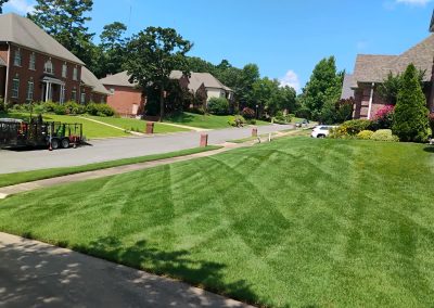 Lush green lawn with neatly striped patterns, showcasing professional lawn care services in a residential neighborhood in Central Arkansas, highlighting APEX Lawn Care's quality work.