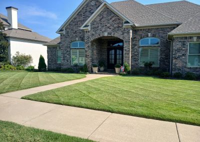 Lawn care service example showcasing well-manicured grass and neatly edged walkways in front of a residential brick home in Central Arkansas.