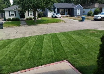 Lush green lawn with neatly striped grass in front of residential homes, showcasing professional lawn care services by APEX Lawn Care in Little Rock, Arkansas.